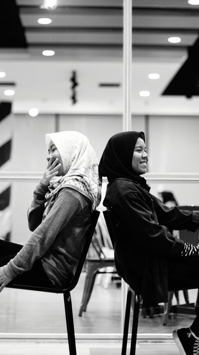 灰度摄影的两个女人坐在椅子上,面带微笑
